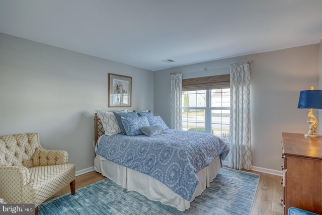 bedroom featuring light wood-style flooring, visible vents, and baseboards