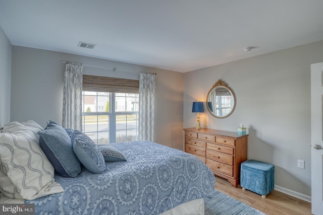 bedroom featuring visible vents, baseboards, and wood finished floors