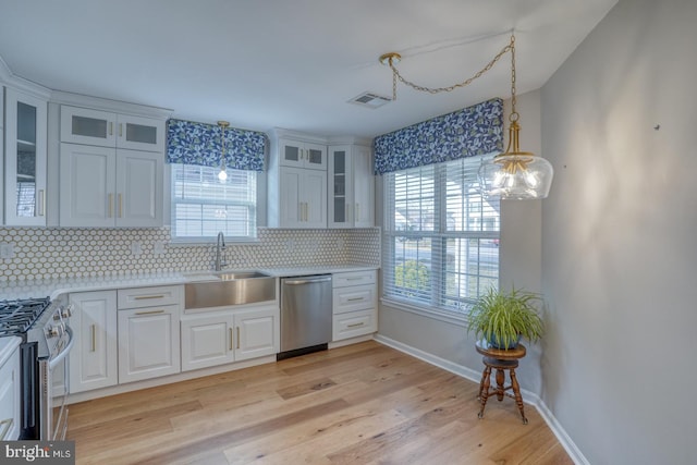 kitchen featuring visible vents, a sink, appliances with stainless steel finishes, tasteful backsplash, and light wood-type flooring