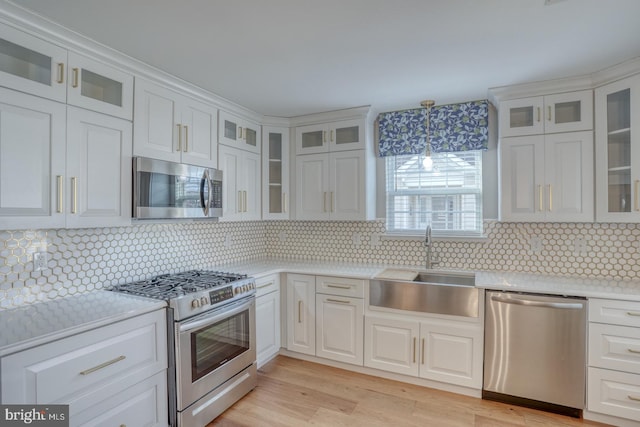 kitchen with light wood finished floors, a sink, light countertops, white cabinets, and appliances with stainless steel finishes