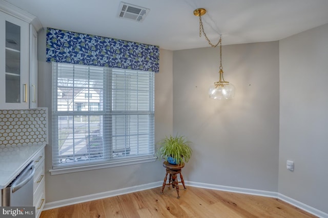 dining room with light wood-type flooring, visible vents, and baseboards