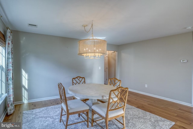 dining room with visible vents, baseboards, a notable chandelier, and wood finished floors