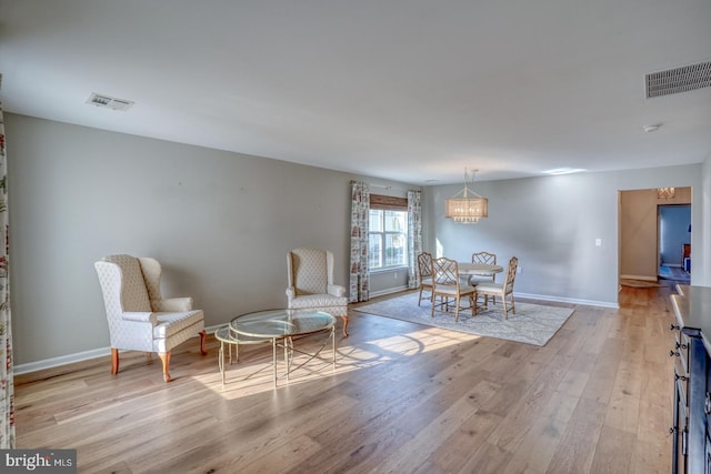 sitting room featuring light wood-type flooring, baseboards, visible vents, and a chandelier