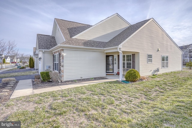 view of front facade featuring a shingled roof and a front lawn