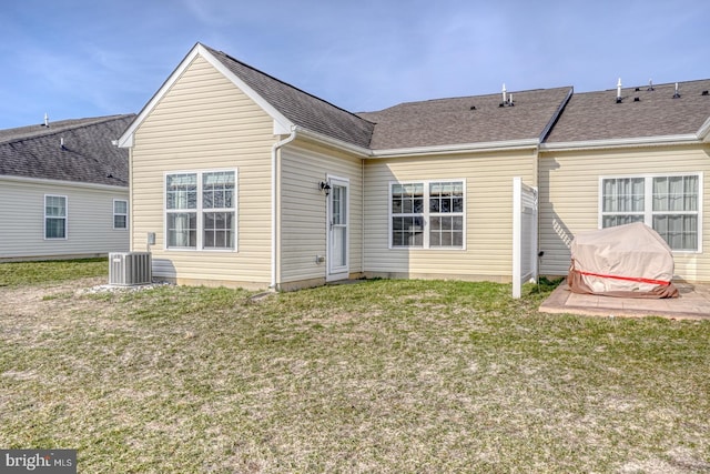 back of property with central AC unit, a lawn, roof with shingles, and a patio area