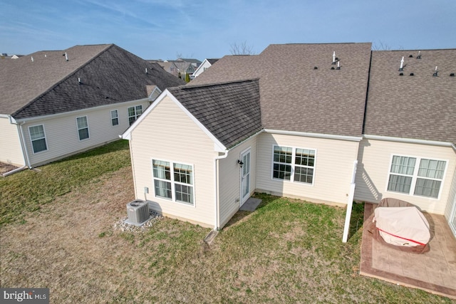 back of house featuring cooling unit, a lawn, and roof with shingles