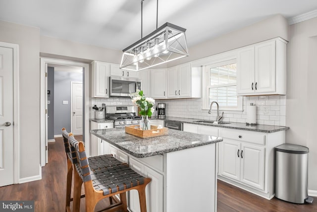 kitchen featuring a kitchen island, dark wood finished floors, white cabinets, stainless steel appliances, and a sink