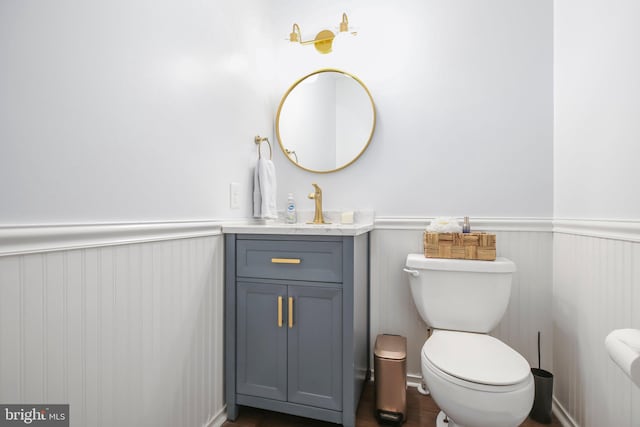 bathroom with vanity, toilet, and wainscoting