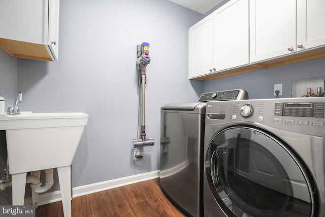 washroom with dark wood-style flooring, cabinet space, baseboards, and separate washer and dryer