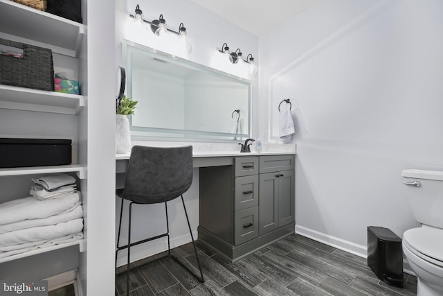 bathroom featuring baseboards, vanity, toilet, and wood tiled floor