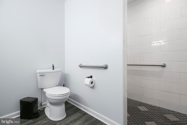 full bathroom with a shower stall, toilet, baseboards, and wood finished floors