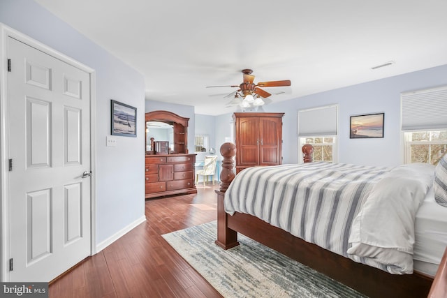 bedroom with visible vents, baseboards, dark wood-style floors, and a ceiling fan