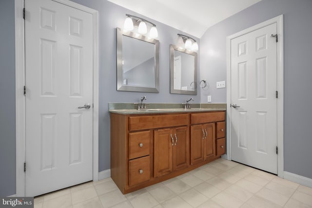 bathroom with double vanity, baseboards, and a sink