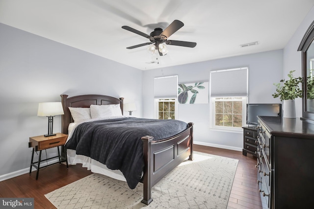 bedroom featuring visible vents, baseboards, dark wood-type flooring, and ceiling fan