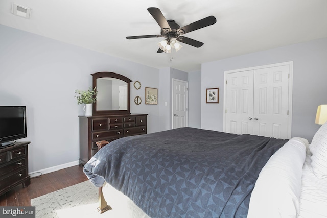 bedroom with visible vents, a ceiling fan, dark wood finished floors, a closet, and baseboards