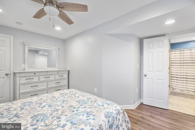 bedroom featuring baseboards, recessed lighting, wood finished floors, ensuite bath, and a ceiling fan