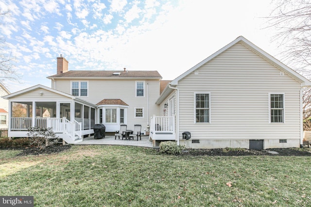 rear view of property with a yard, a patio area, a sunroom, and crawl space