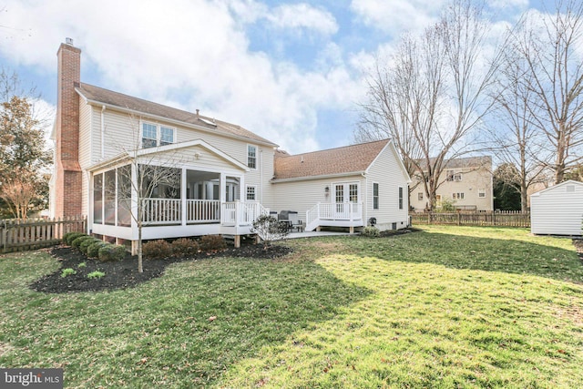 back of house with a yard, a chimney, a fenced backyard, and a sunroom