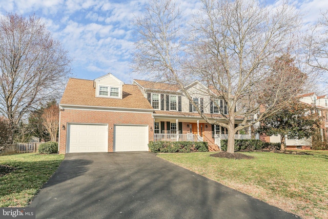 view of front of home with driveway, an attached garage, covered porch, a front lawn, and brick siding