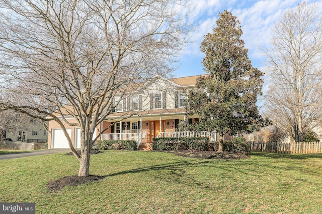 view of front of home featuring brick siding, a front lawn, fence, a porch, and driveway