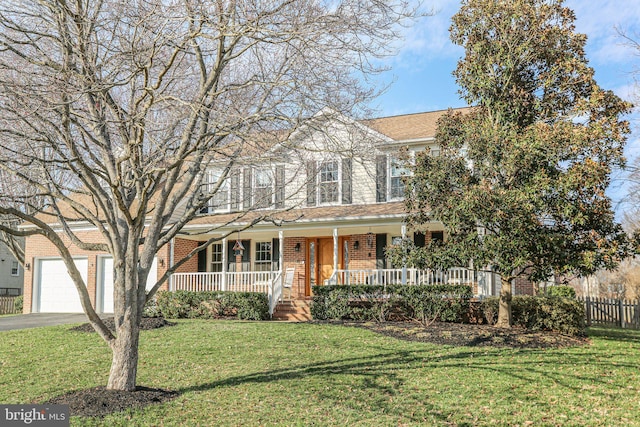 view of front of property with driveway, a front lawn, fence, covered porch, and brick siding