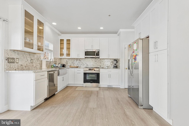 kitchen featuring backsplash, crown molding, appliances with stainless steel finishes, light wood-style floors, and white cabinetry