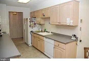 kitchen featuring a sink, white appliances, and dark countertops