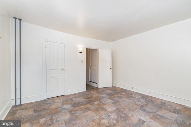 unfurnished bedroom with baseboards and stone finish flooring