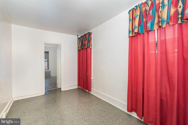 unfurnished room featuring baseboards and radiator