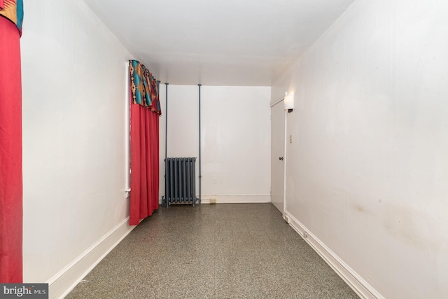 spare room featuring baseboards and radiator