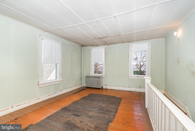 spare room featuring radiator heating unit and hardwood / wood-style flooring