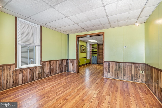 unfurnished room featuring wood finished floors, a wainscoted wall, and wood walls