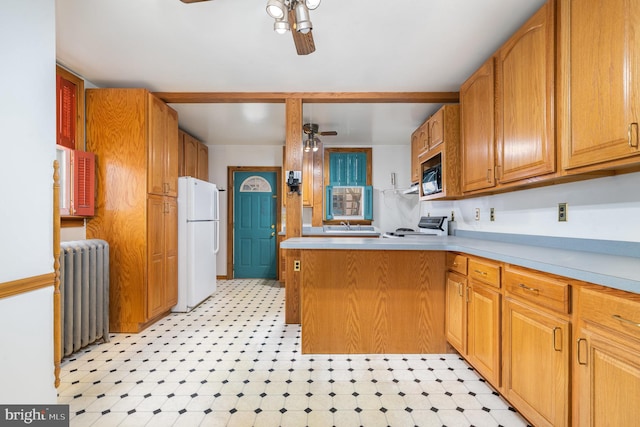 kitchen featuring radiator, a ceiling fan, light floors, and freestanding refrigerator