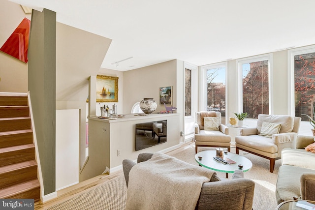 living room with baseboards, track lighting, wood finished floors, and stairs