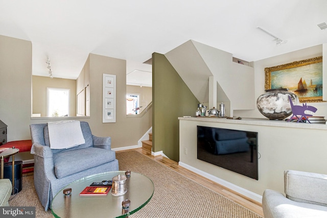 living room with track lighting, stairway, wood finished floors, and visible vents