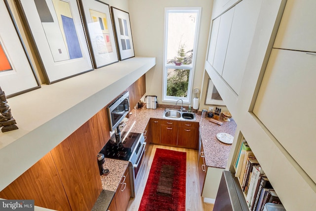 kitchen with brown cabinetry, modern cabinets, light stone counters, and a sink