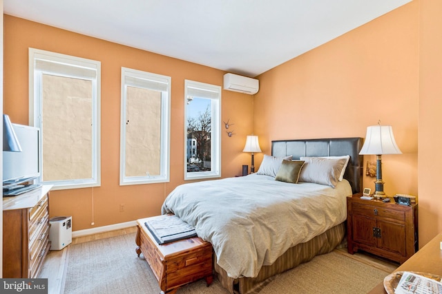 bedroom featuring a wall mounted AC, baseboards, and wood finished floors