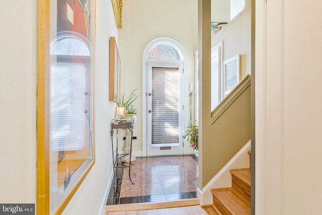 foyer entrance with stairway and baseboards