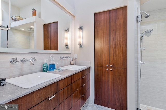 bathroom featuring double vanity, tasteful backsplash, a tile shower, and a sink