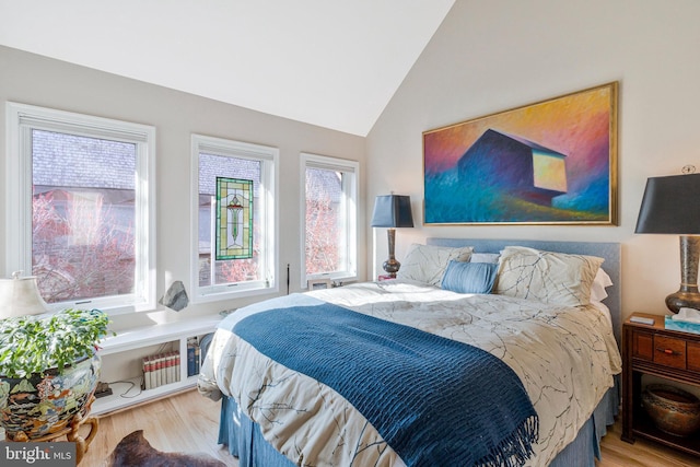 bedroom with vaulted ceiling and wood finished floors