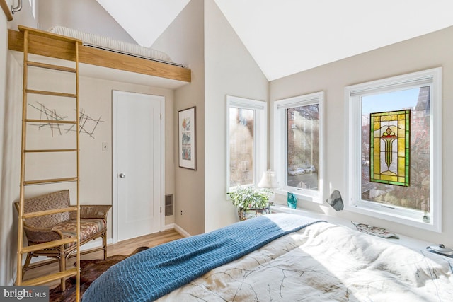 bedroom with baseboards, lofted ceiling, and wood finished floors