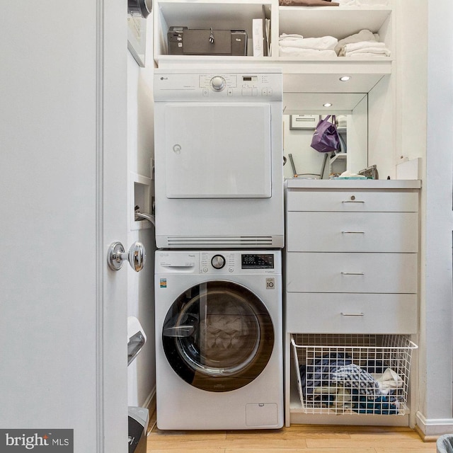 washroom with wood finished floors, laundry area, and stacked washing maching and dryer