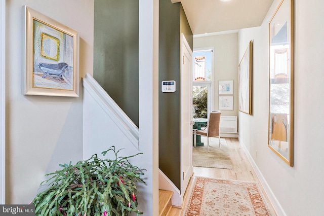 hall featuring light wood-style flooring, stairs, and baseboards