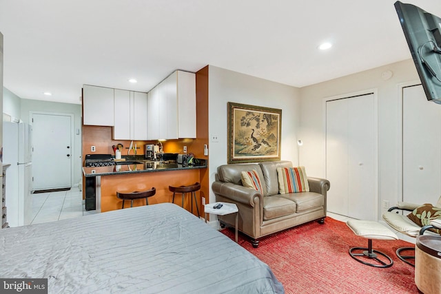 bedroom featuring light tile patterned floors, recessed lighting, multiple closets, and freestanding refrigerator