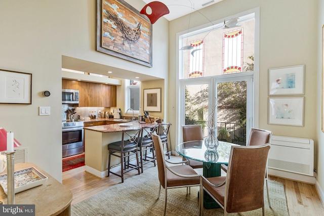 dining space with light wood-type flooring and a high ceiling