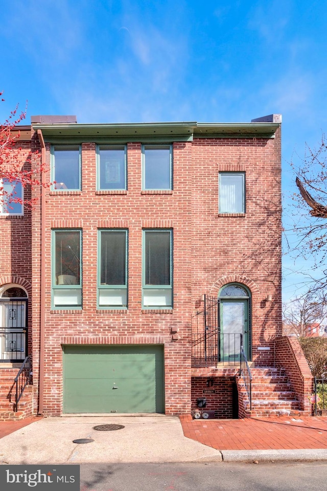 multi unit property featuring a garage, brick siding, and concrete driveway