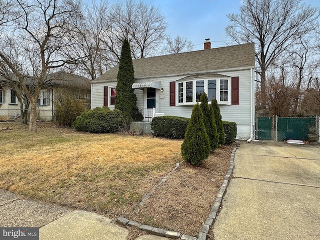 view of front of home featuring a front yard, a gate, fence, and roof with shingles