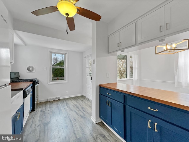 kitchen with gas range, blue cabinets, visible vents, and butcher block counters