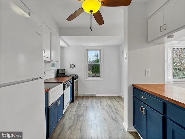 kitchen with wooden counters, decorative backsplash, white appliances, and blue cabinets