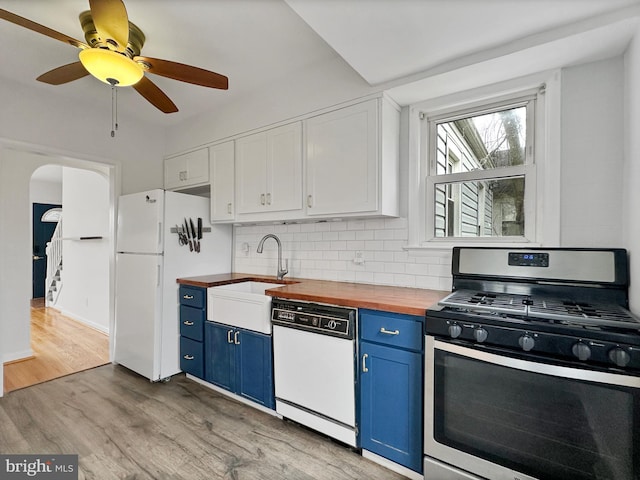 kitchen featuring white appliances, blue cabinetry, arched walkways, light wood-style floors, and wood counters